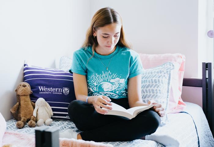 Student sitting on bed reading